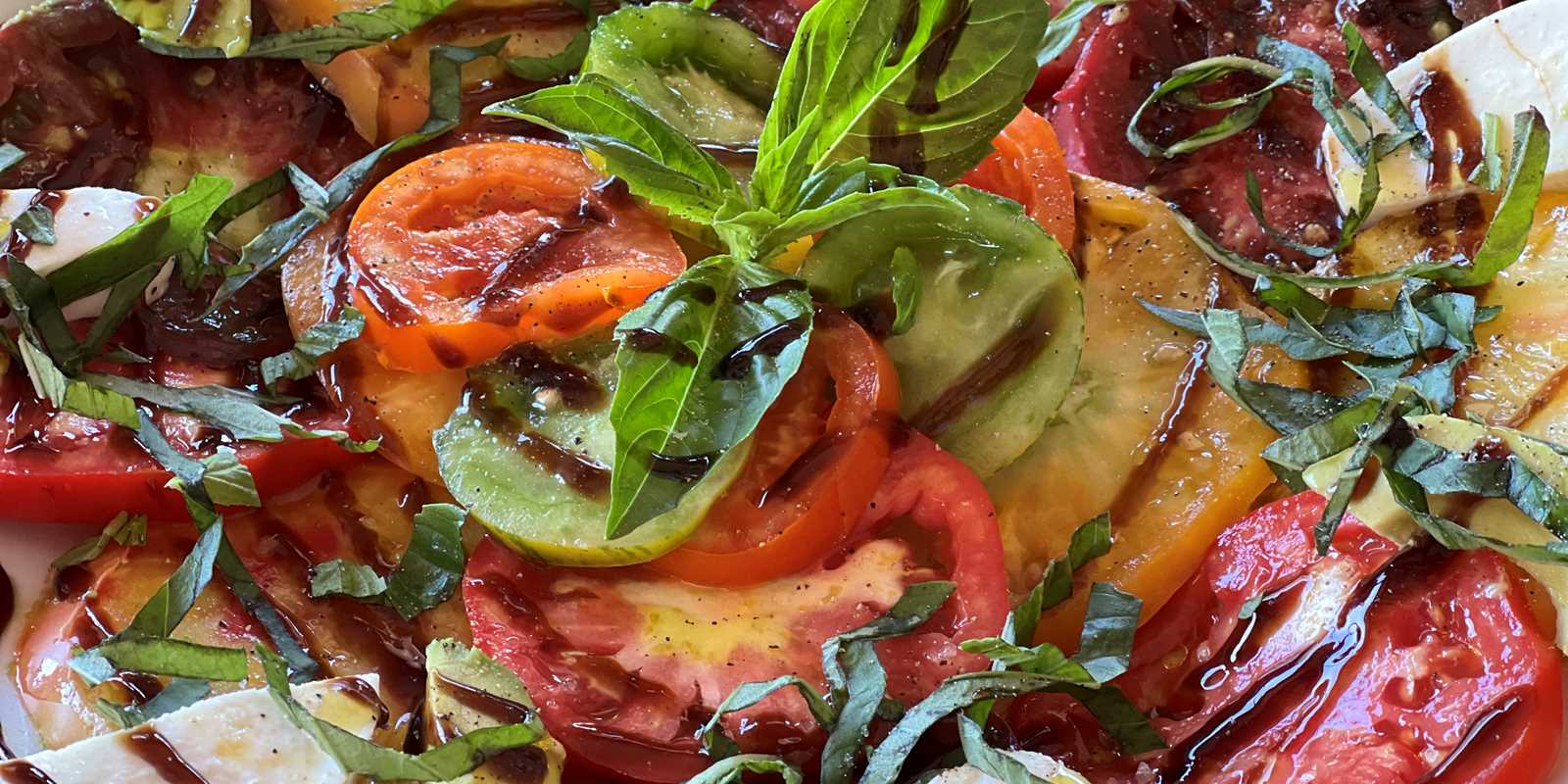 Tomato plate with fresh mozzarella, avocado and balsamic glaze.