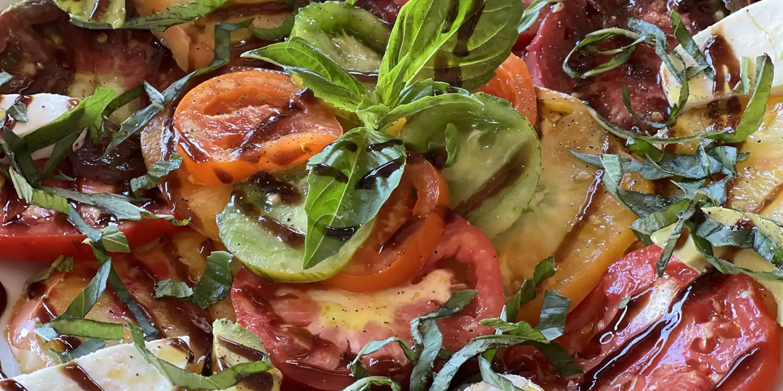 Tomato plate with fresh mozzarella, avocado and balsamic glaze.