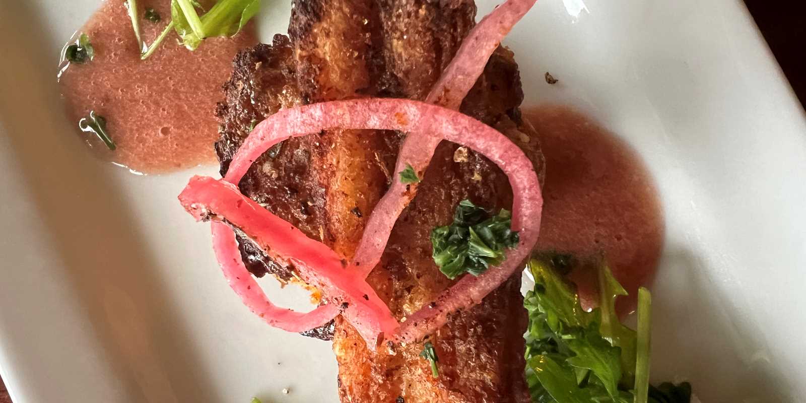 Pork belly on a swim biscuit with pickled red onion